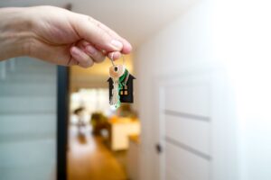 Hand met een sleutelbos met huissleutelhanger in een woning